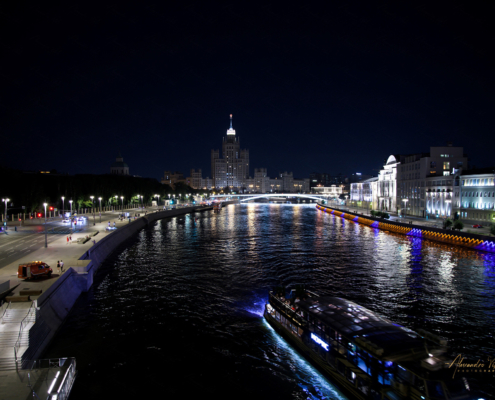 Battello sul fiume Moscova di notte con grattacielo staliniano illuminato sullo sfondo