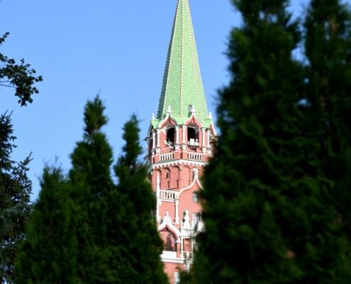 Cuspide della Torre Troitskaya a Mosca parzialmente nascosta da alberi verdi e cielo azzurro